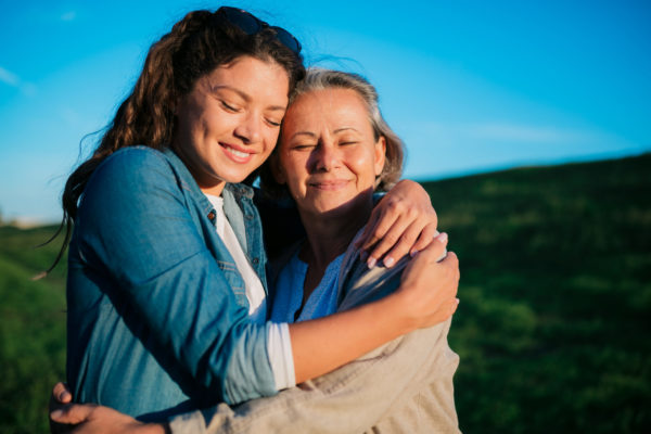 portrait-of-loving-daughter-embracing-her-mother-outside-in-nature