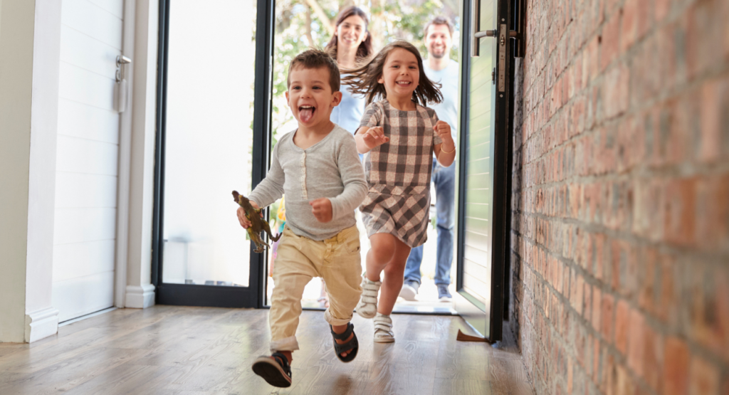 zwei kleine Kinder die lachend in ein Haus rennen